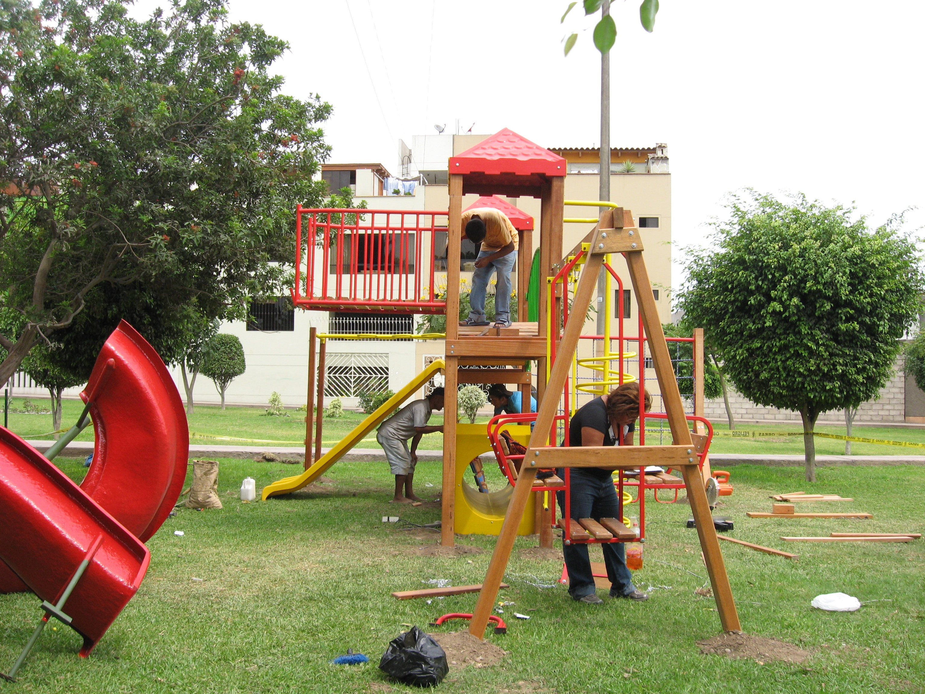 Equipo instalando juego infantil de madera en parque con árboles